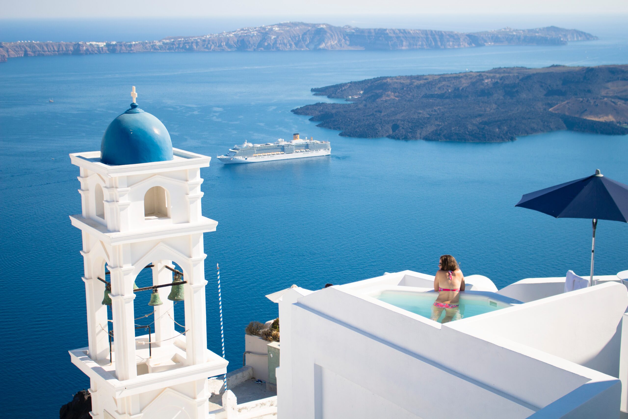 Luxury travel image of a woman in Greece gazing out from a pool